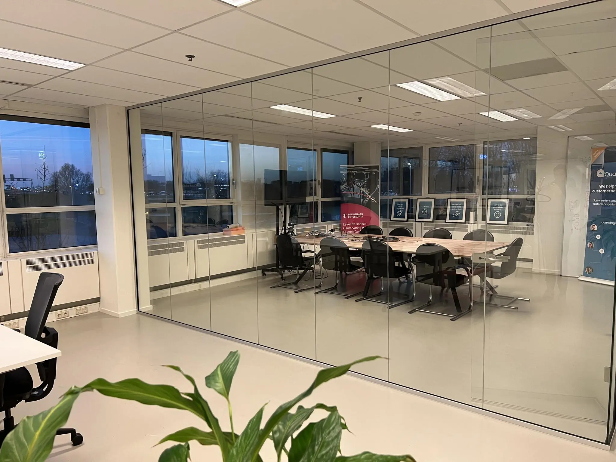 Vergaderruimte in Rivium Quadrant met glazen wanden, moderne inrichting en zicht op posters en een presentatiescherm.